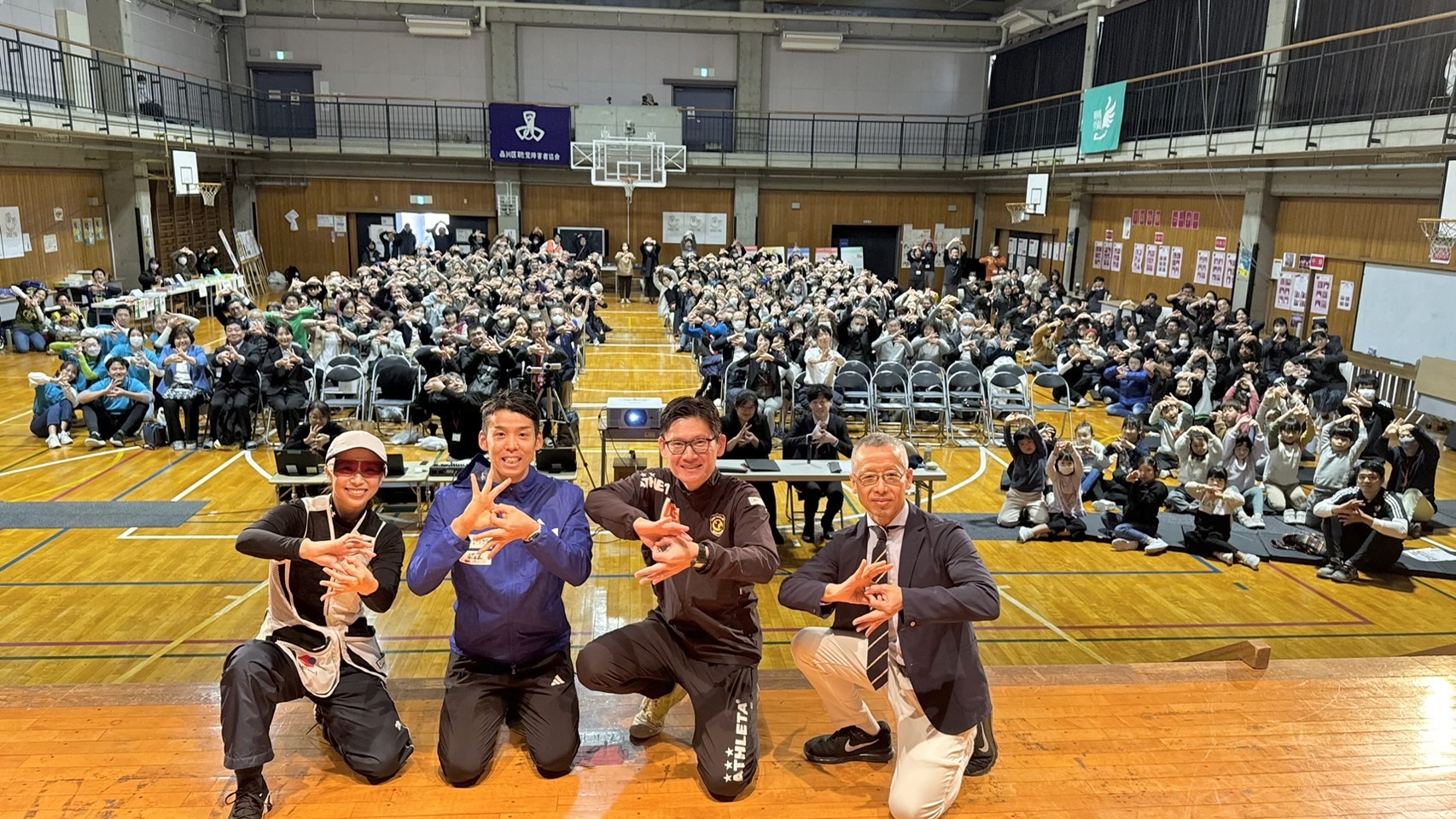 体育館で多くの観客と3名の登壇者と写る植松さんの写真
