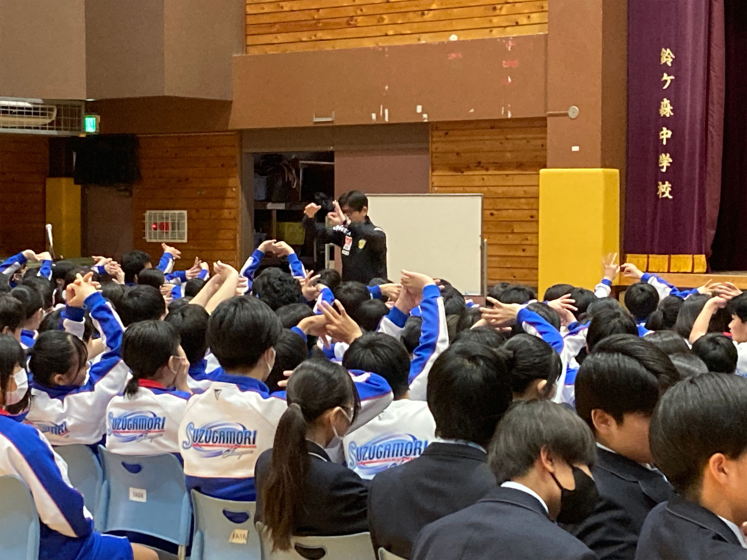 体育館で子供たちに手話をしている植松さんの写真