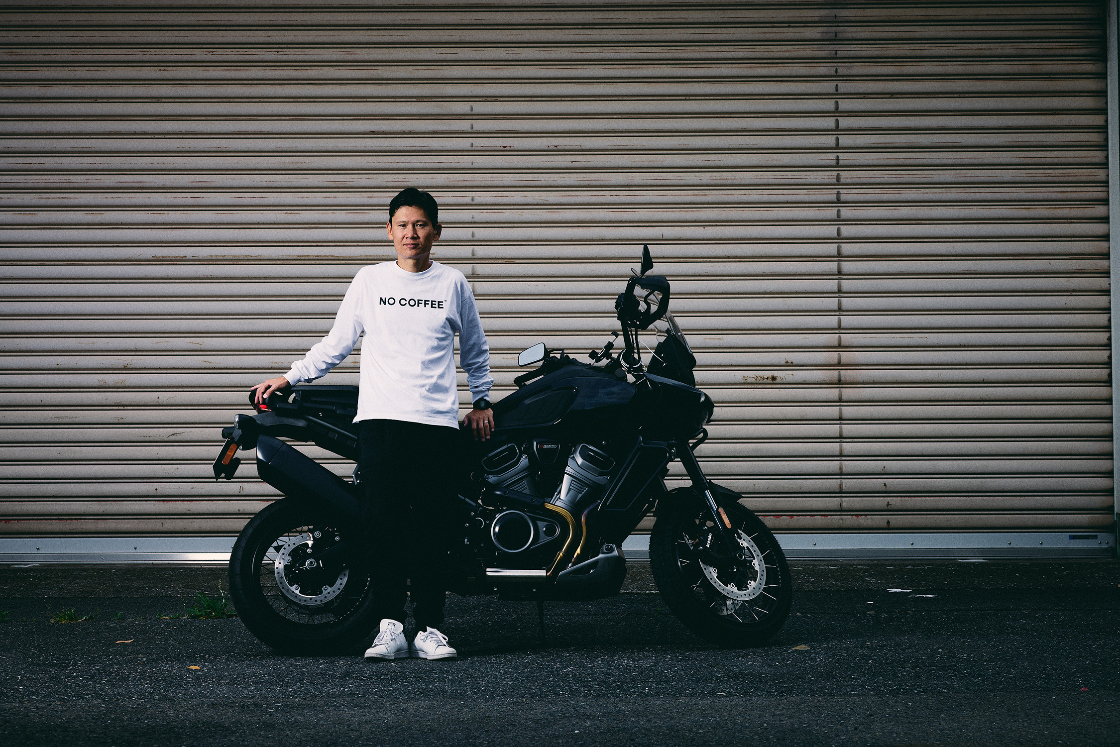 大型バイクの横に寄りかかっている植松さんの写真
