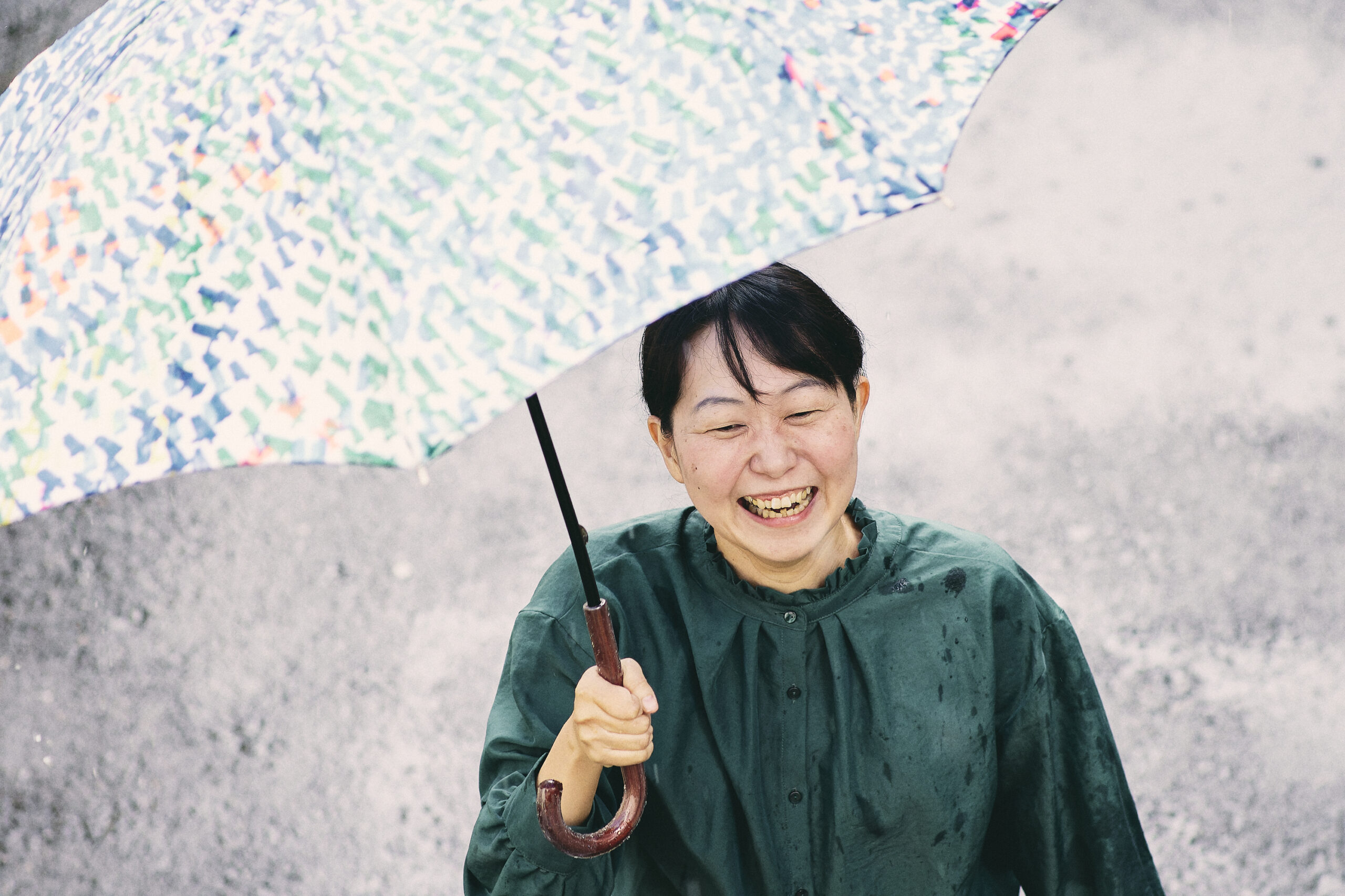 傘をさして笑っている菊永さんの写真