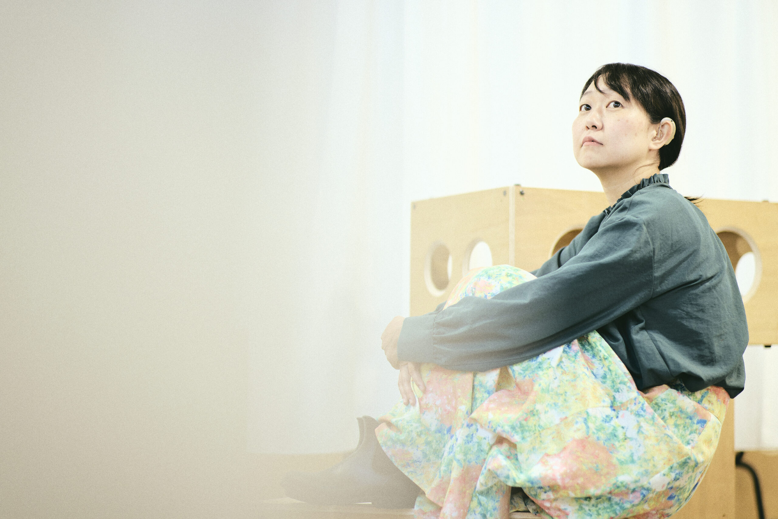 体育座りをして斜め上を見つめている菊永さんの写真