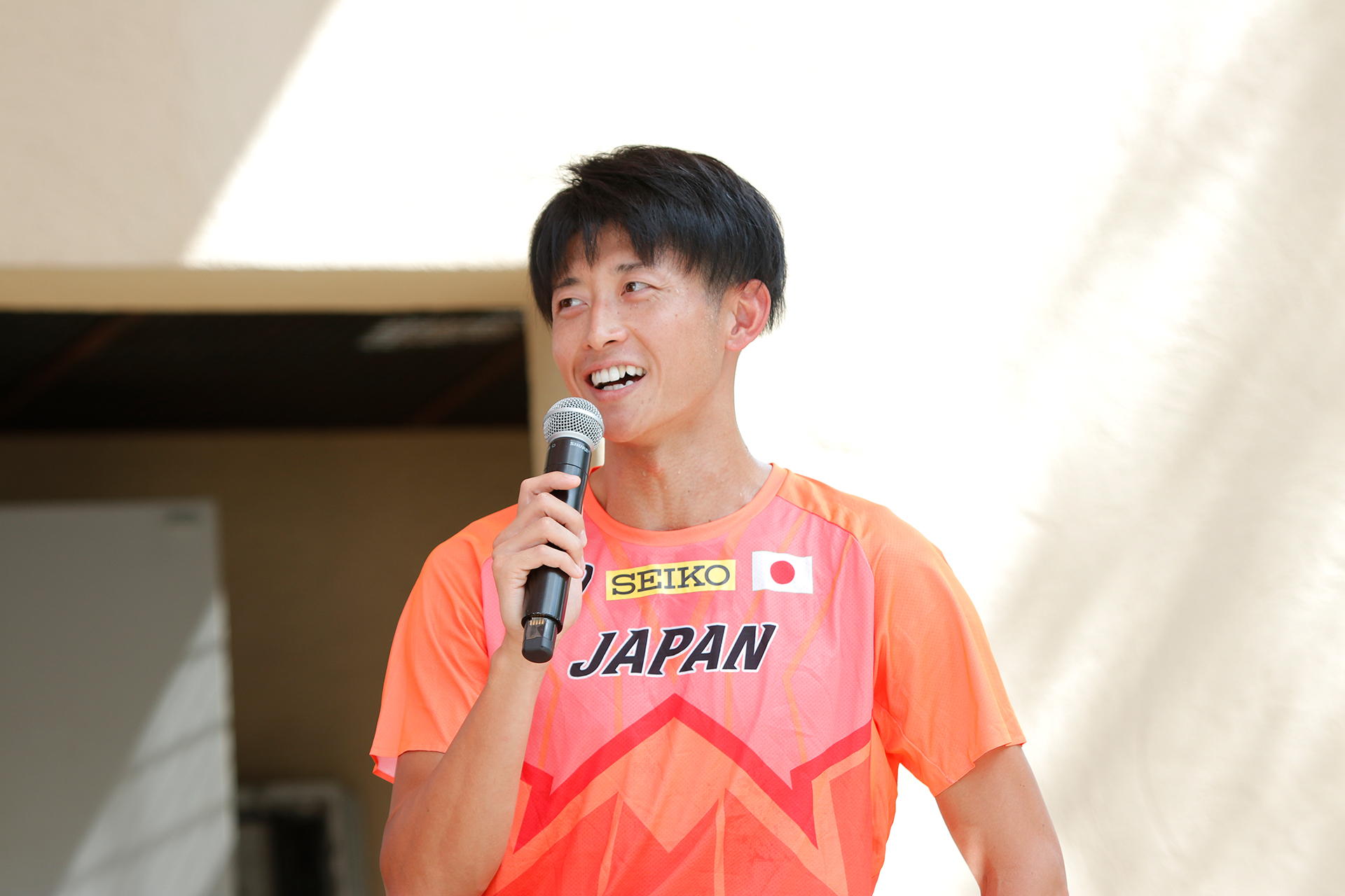 マイクを持った佐藤選手が微笑みながら話をしている写真