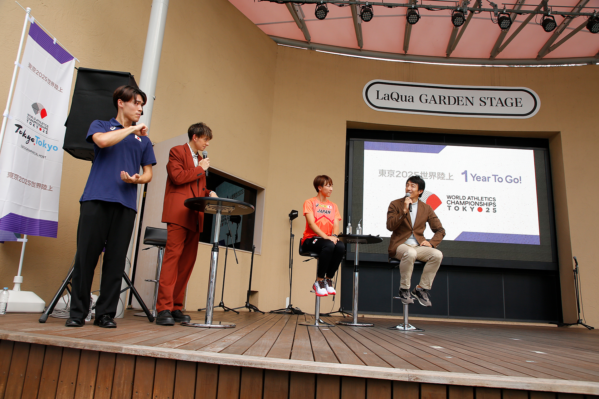 話をしている朝原さんを見ている寺田選手とハリーさん、その横に通訳している手話通訳者の写真