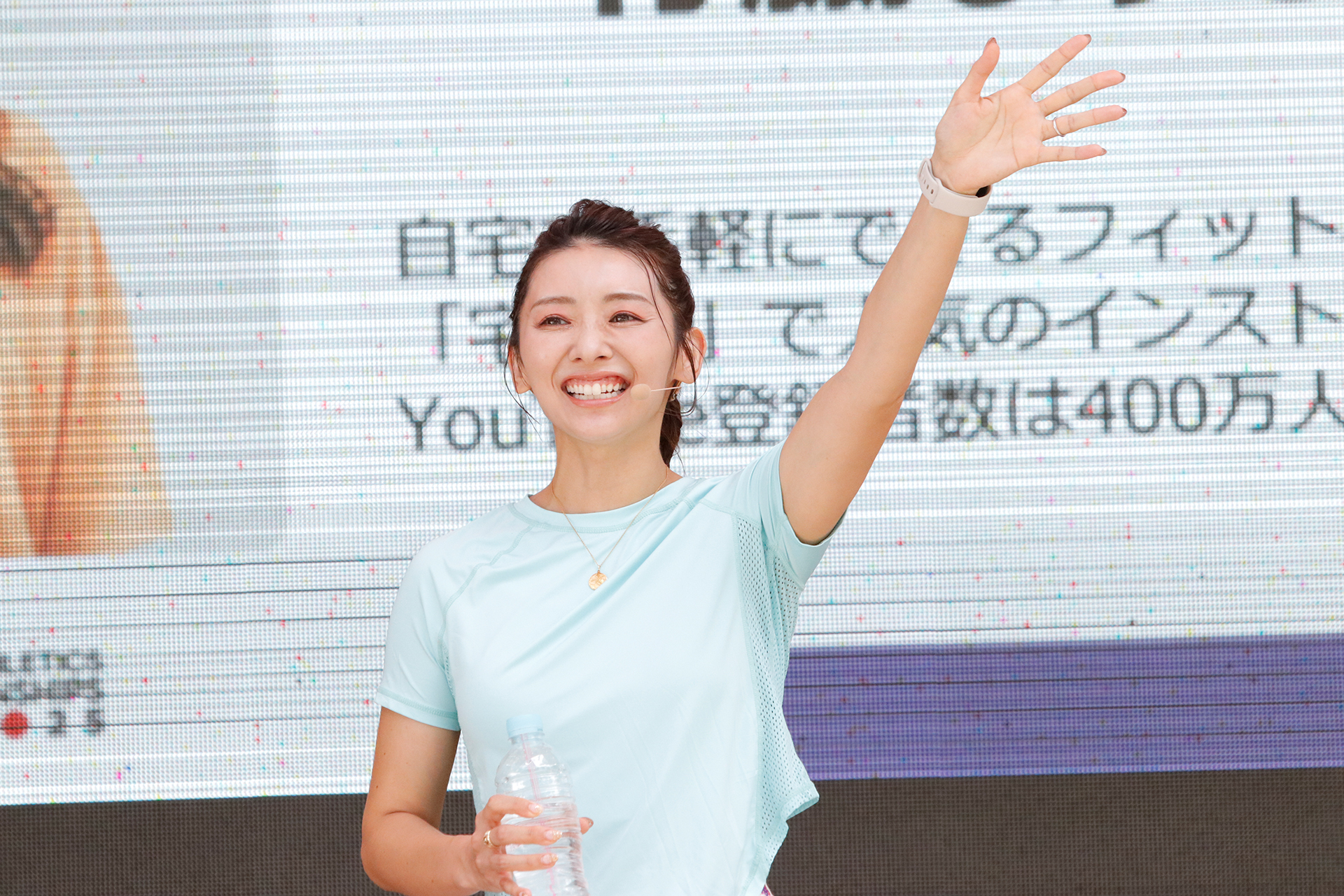 左手を上げて参加者に挨拶をしている竹脇さんの写真