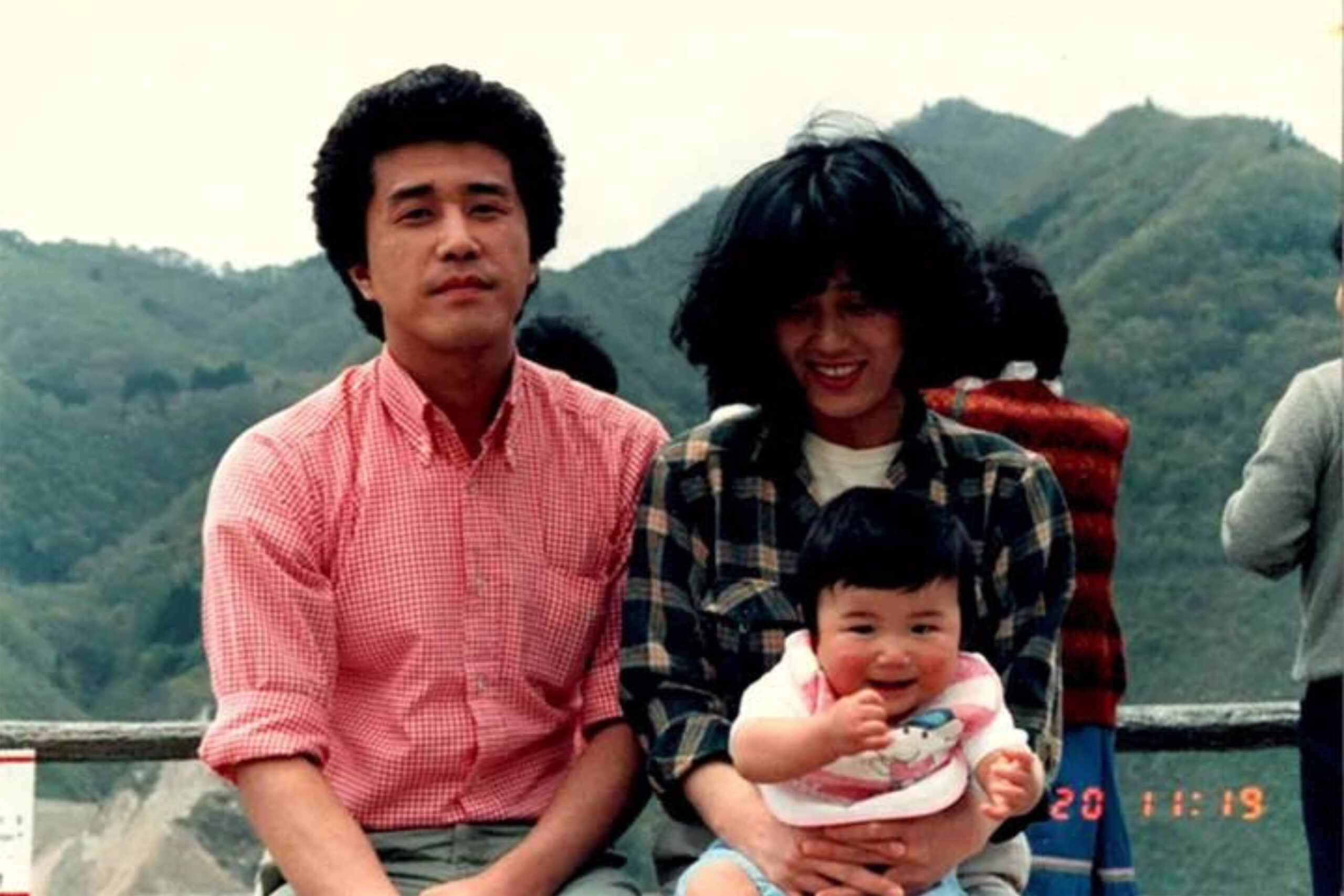 山々を背景に父、母といっしょに写る赤ちゃんのときの五十嵐さんの写真