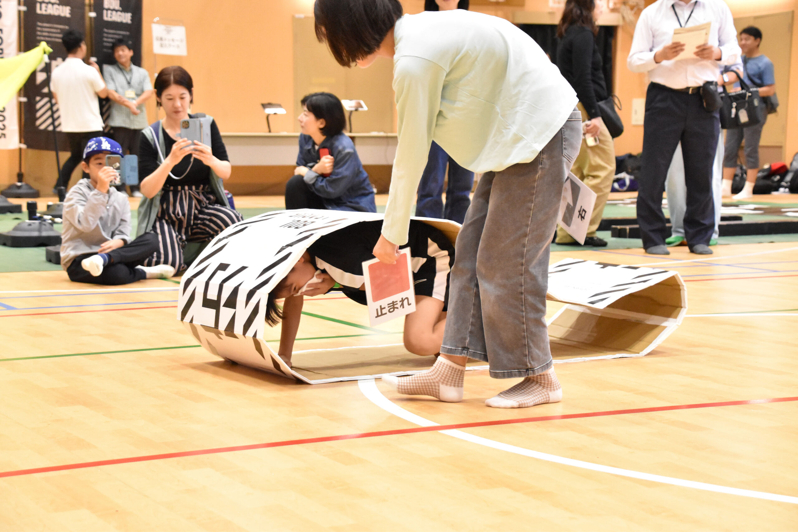 キャタピラに入っている参加者に止まれの紙を見せている女性の写真