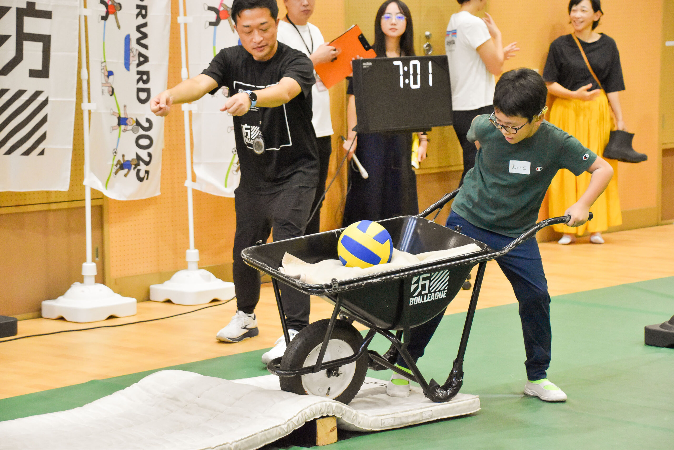 毛布とバレーボールを積んだ一輪手押し車を押している参加者の写真
