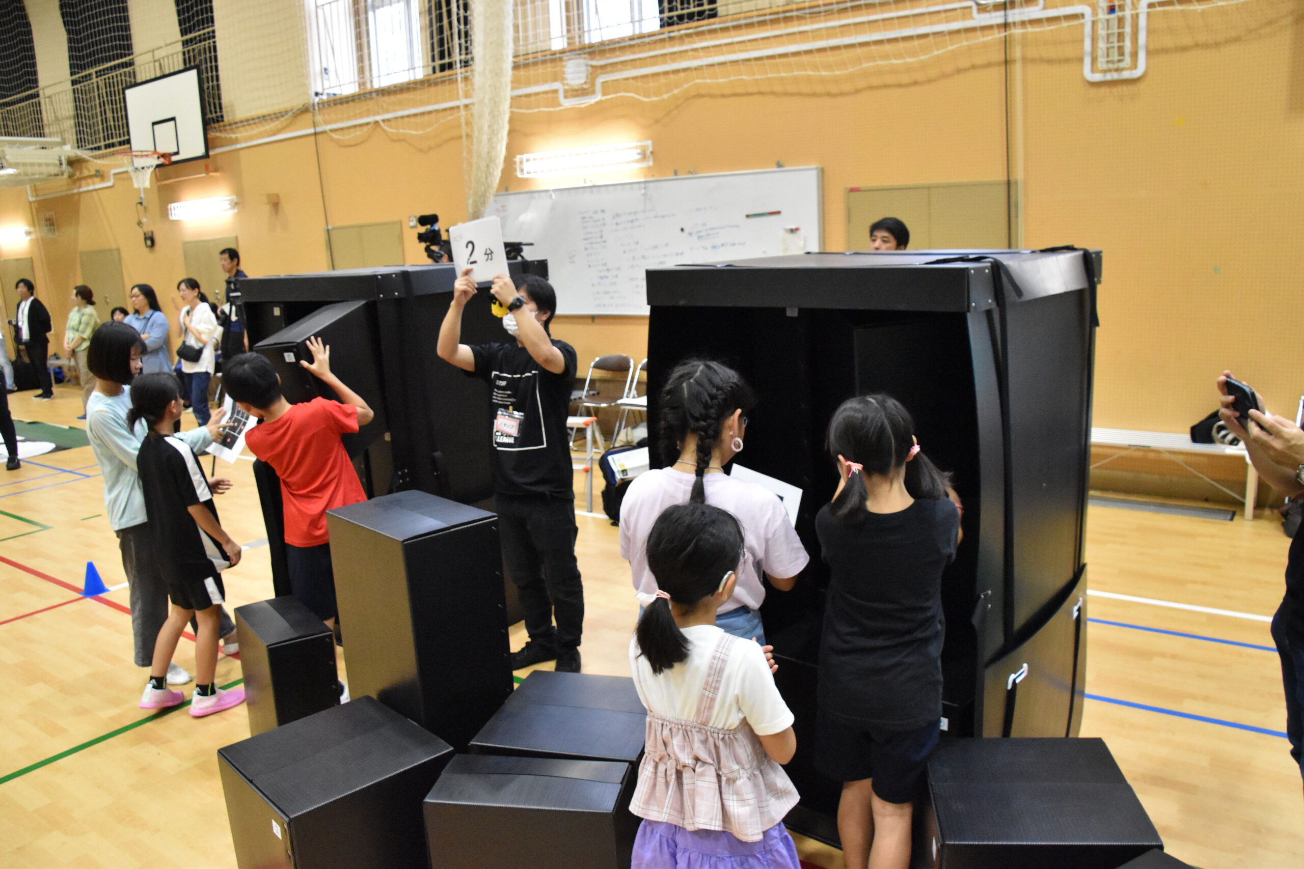 黒い大きな箱の中に小さな箱を入れようとしている参加者の写真
