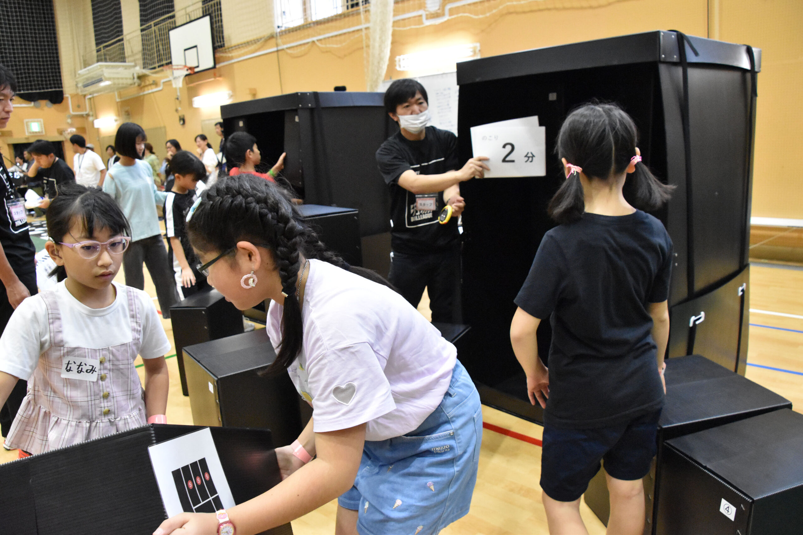 2分と書かれた紙を見せているスタッフと箱を入れようとしている参加者の写真