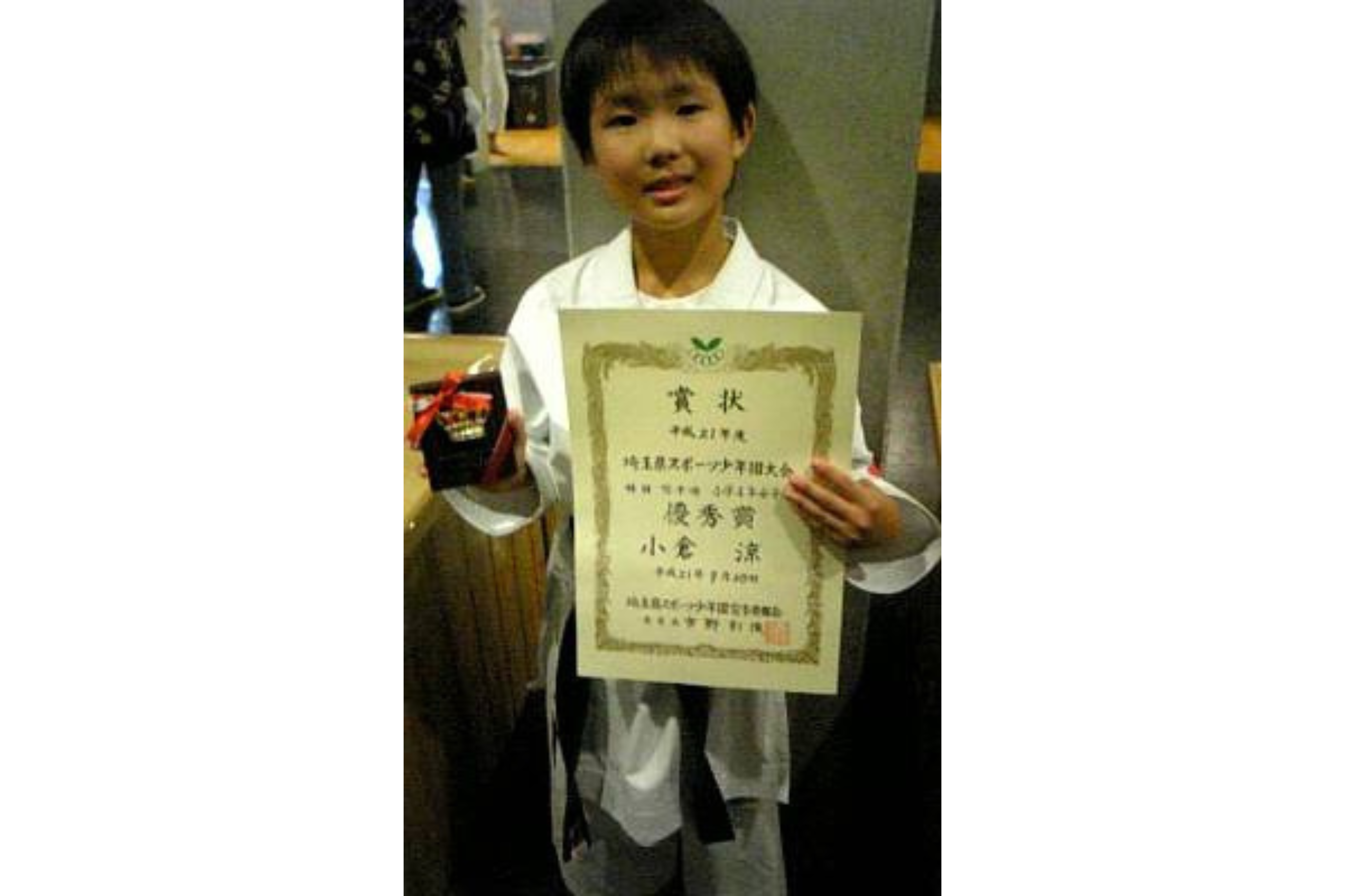 The photo of Ogura as an elementary school student with her award certificate and plaque.